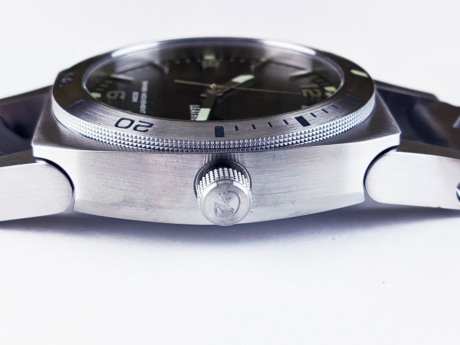 Close-up stainless steel wristwatch crystal inspected for surface scratches