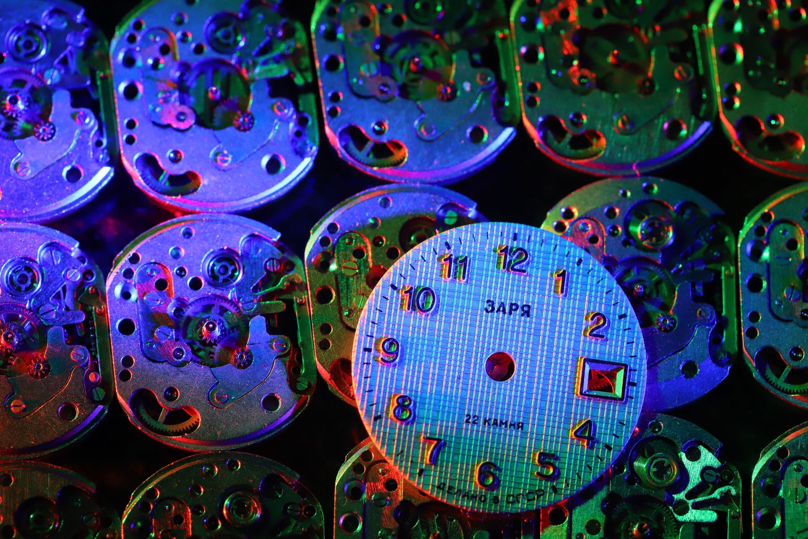 Set of watch movements and a watch dial arranged on a dark surface