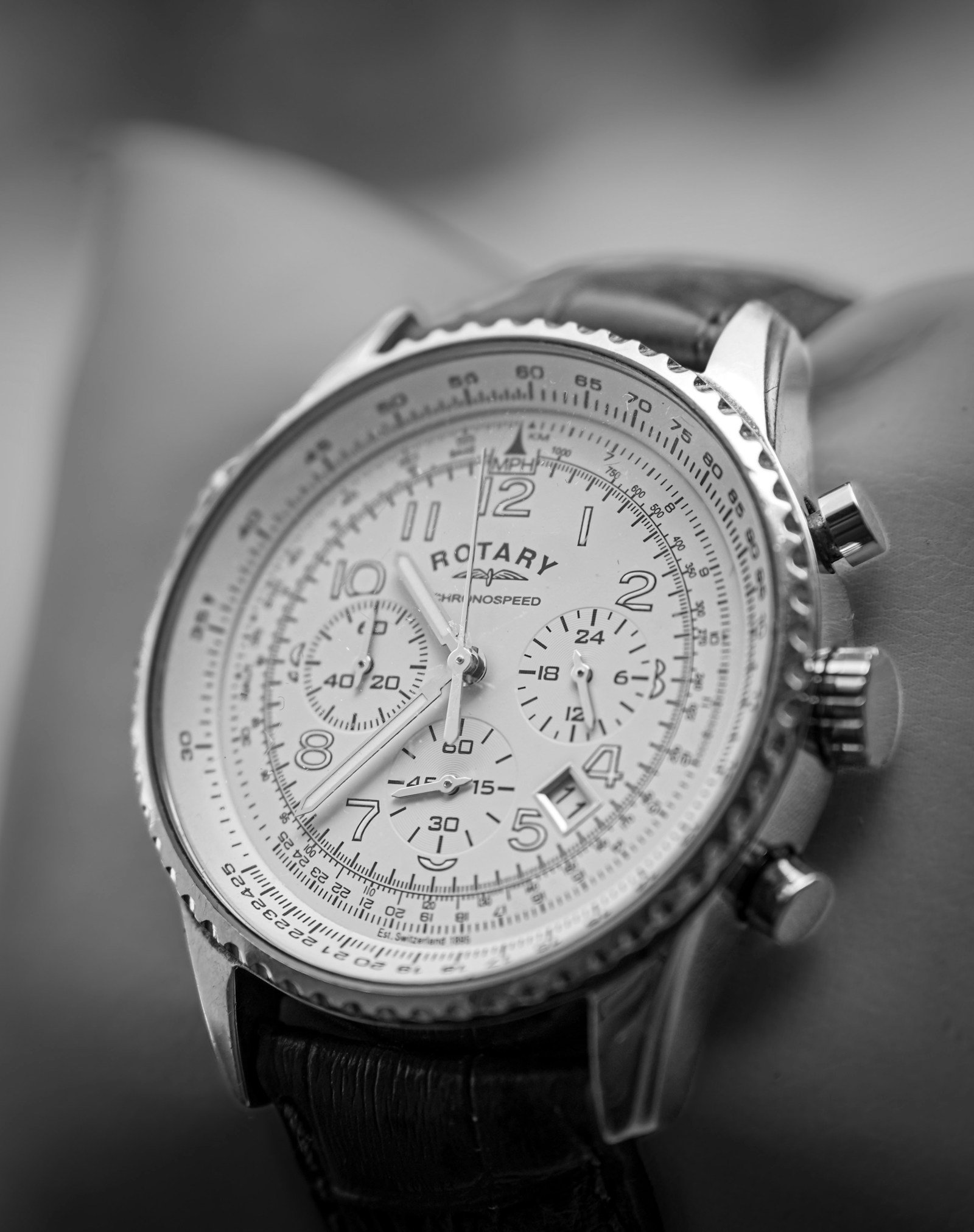 Black chronograph wristwatch photographed in close-up under soft light