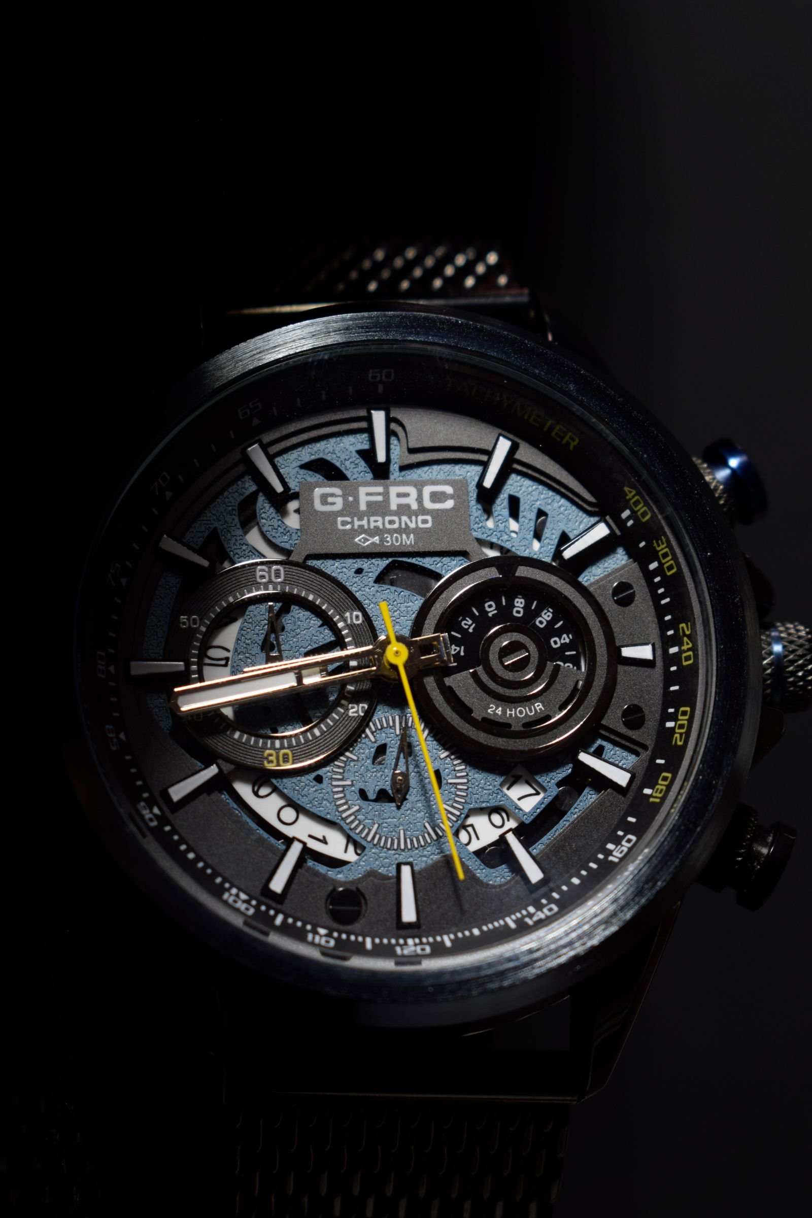 Macro detail of a black chronograph watch dial with subdials and hands