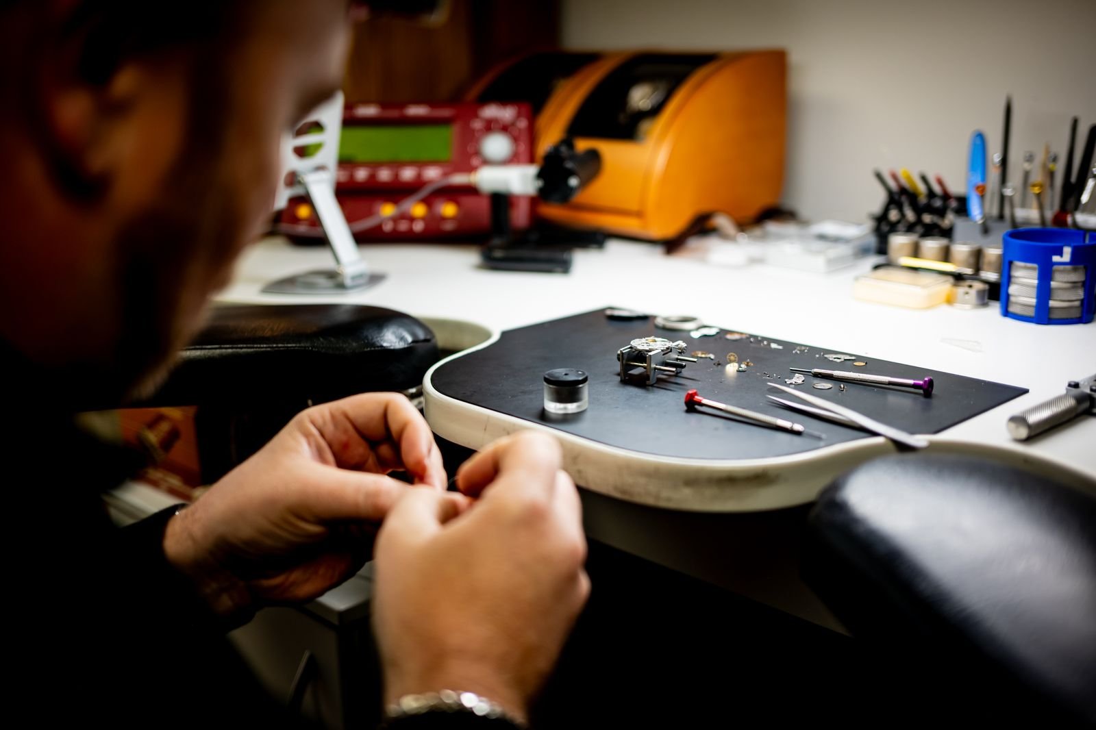 Professional watchmaker resizing and checking a wristwatch bracelet at a workbench