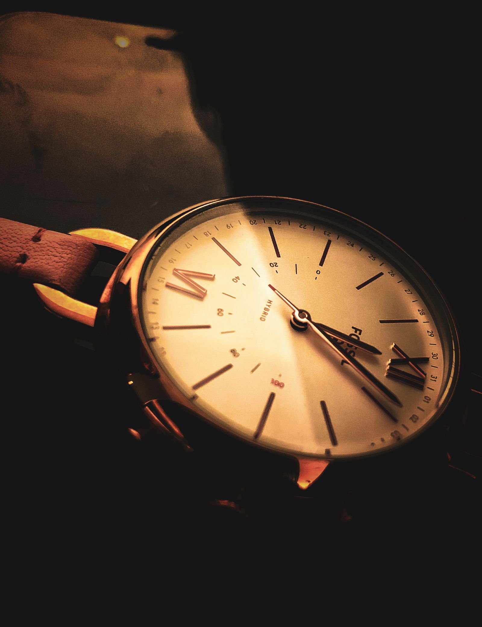 Elegant wristwatch dial photographed in warm light to show crystal reflections