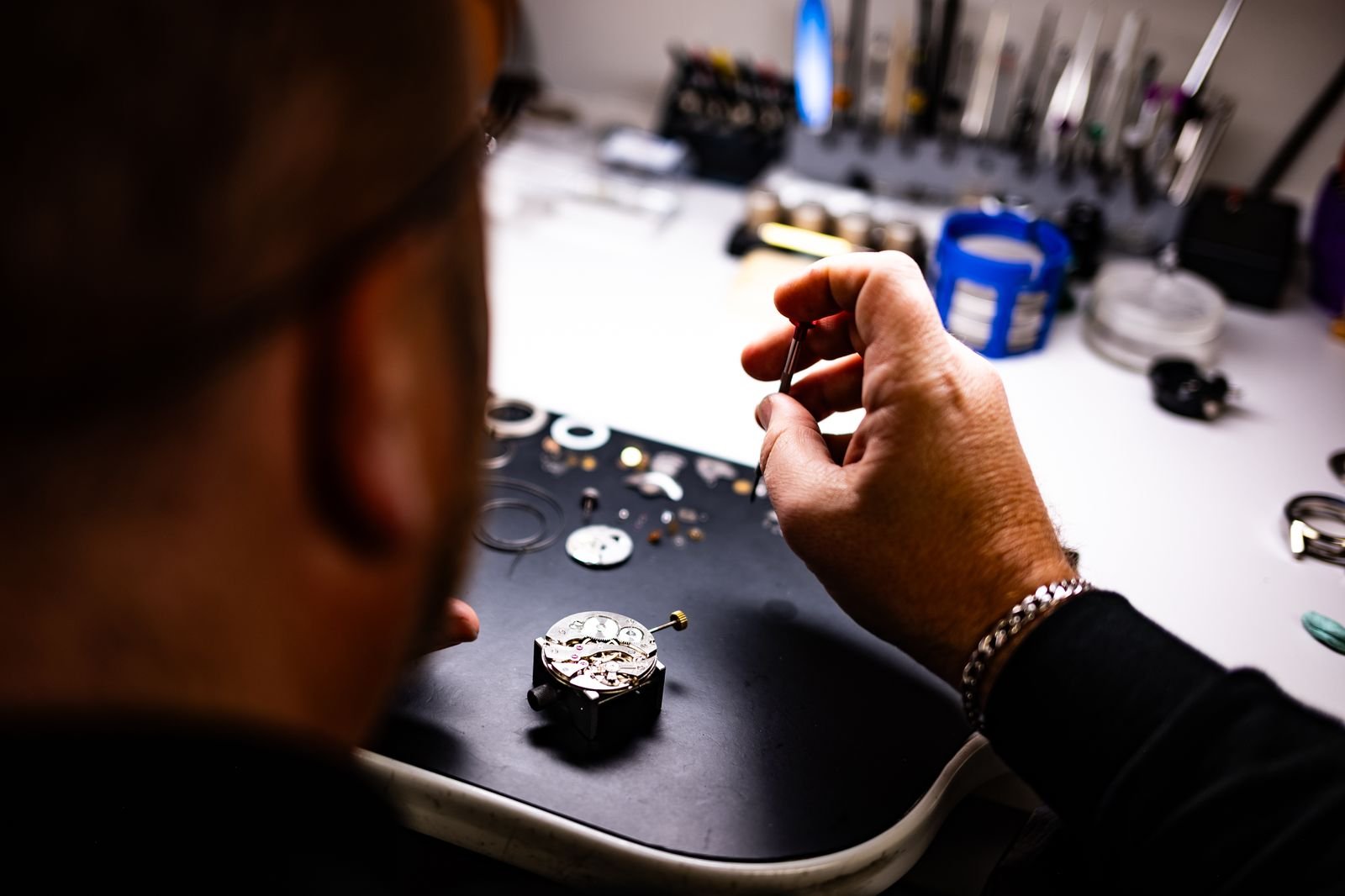 Watchmaker assembling an automatic watch movement at a workbench