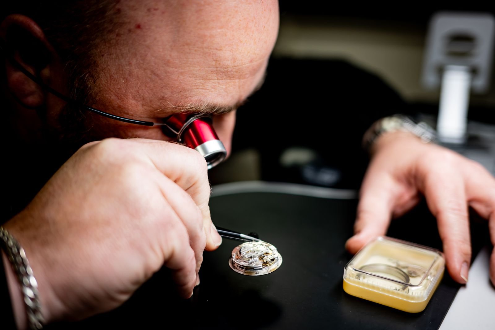 Professional watchmaker using a loupe to inspect a movement during authentication