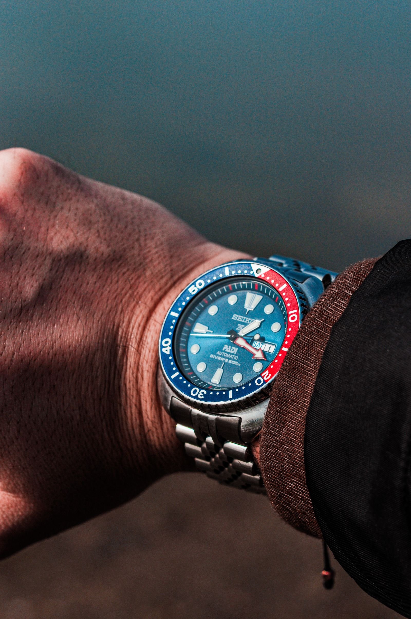 Blue-dial stainless steel watch examined while authenticating an Omega Seamaster Diver 300M
