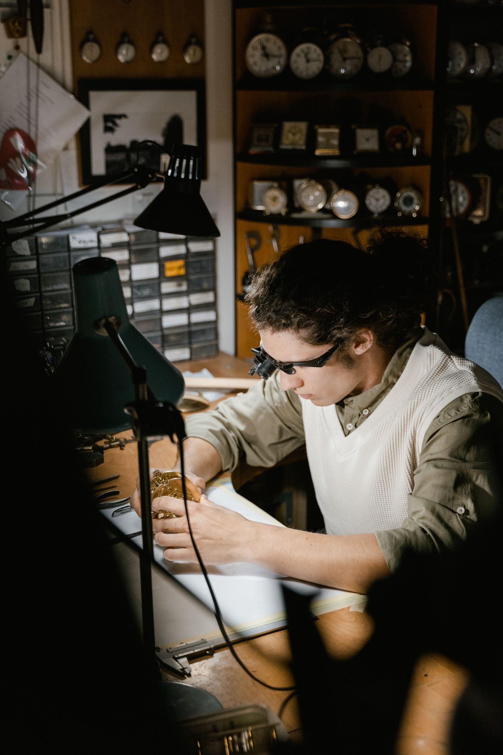 Watchmaker inspecting a mechanical timepiece for balance and escapement faults