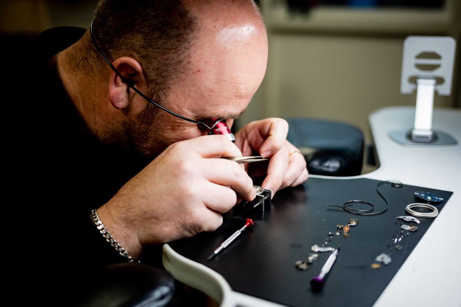 Watchmaker using specialized tools to inspect mechanical watch components
