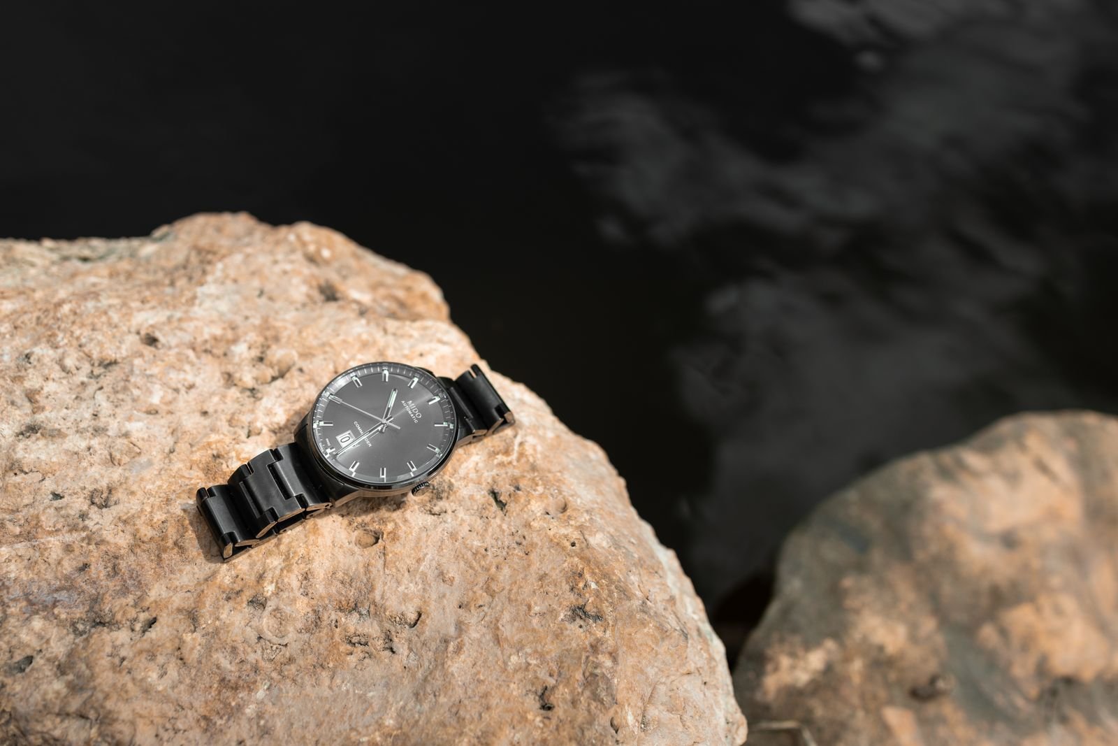 Black wristwatch near water before a moisture and seal inspection