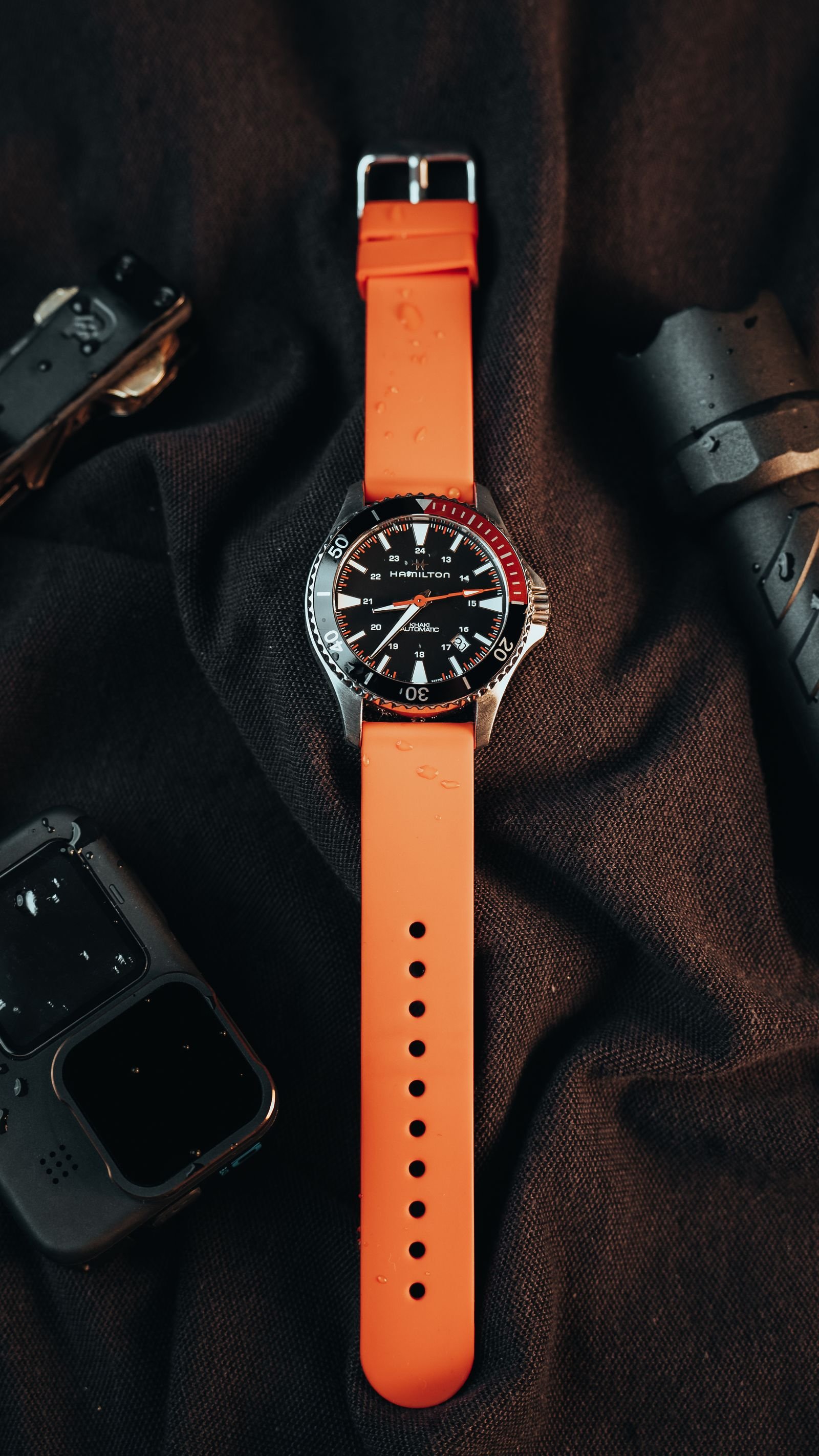 Dive-style watch with a dark bezel insert photographed beside outdoor gear