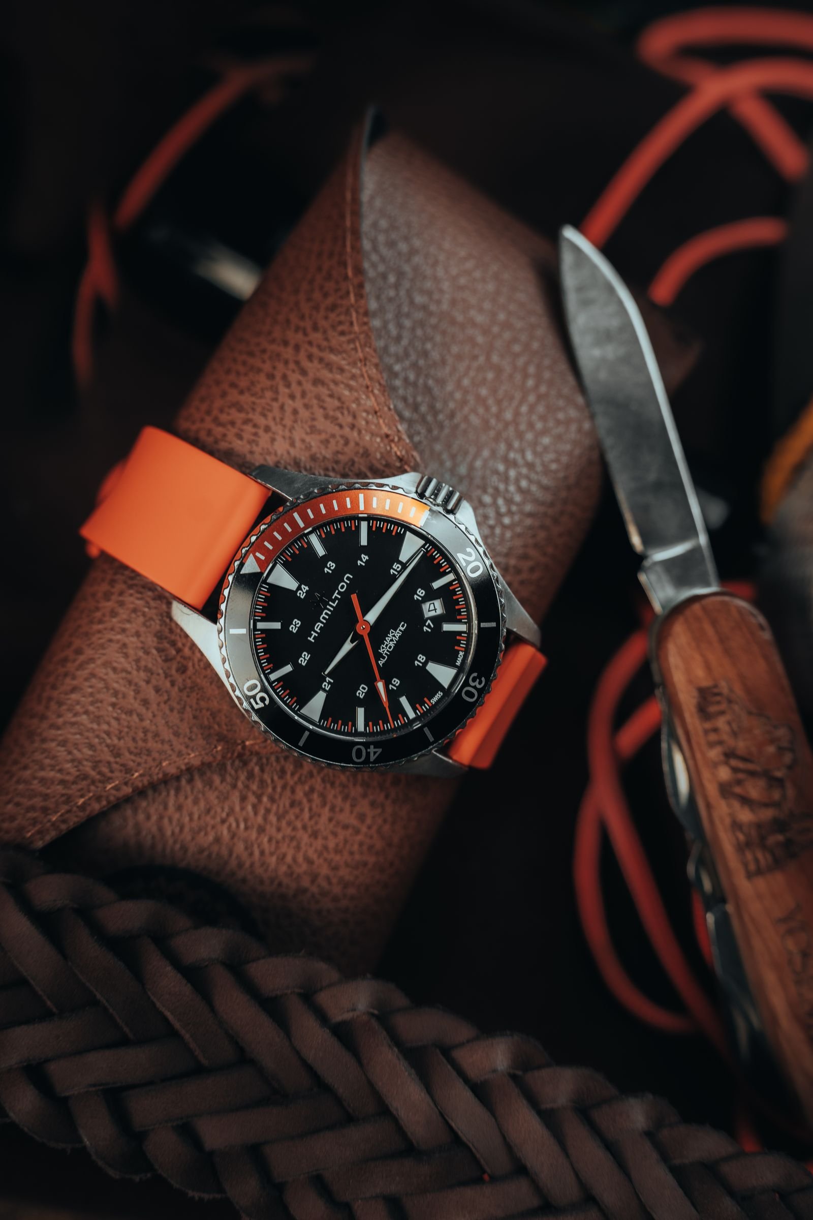 Sports watch and pocketknife illustrating the impact and abrasion risks of daily wear